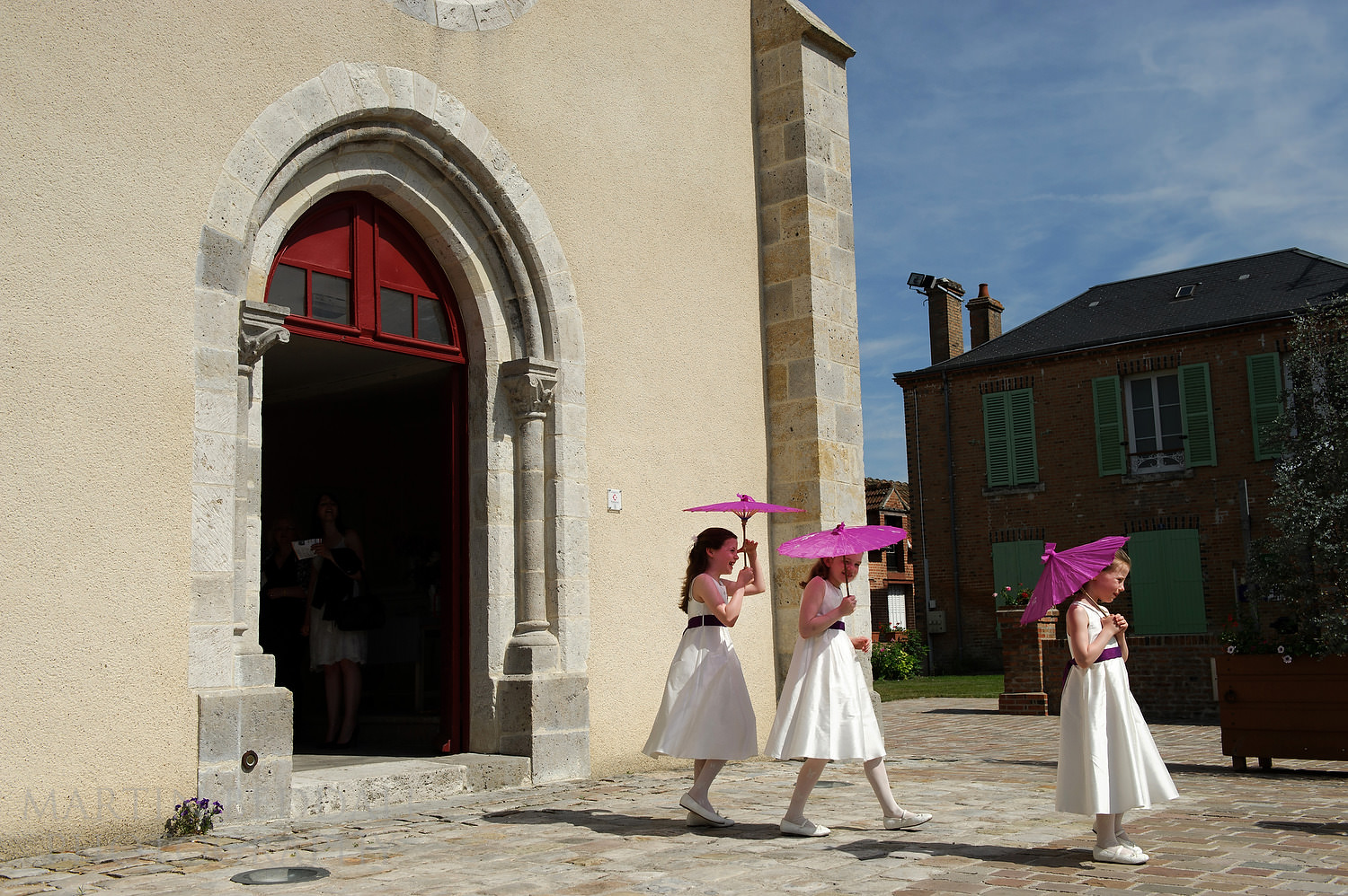 Flower girls with sun umbrellas at Notre Dame de Ménestreau-en-Villette