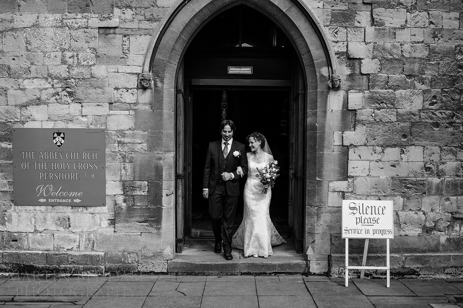 Bride and groom walk out of Pershore Abbey