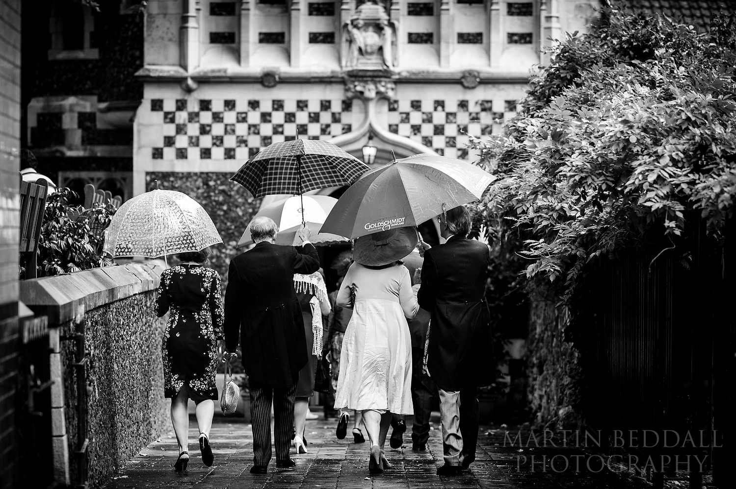 Wedding guests arrive in the rain at St Bart's church