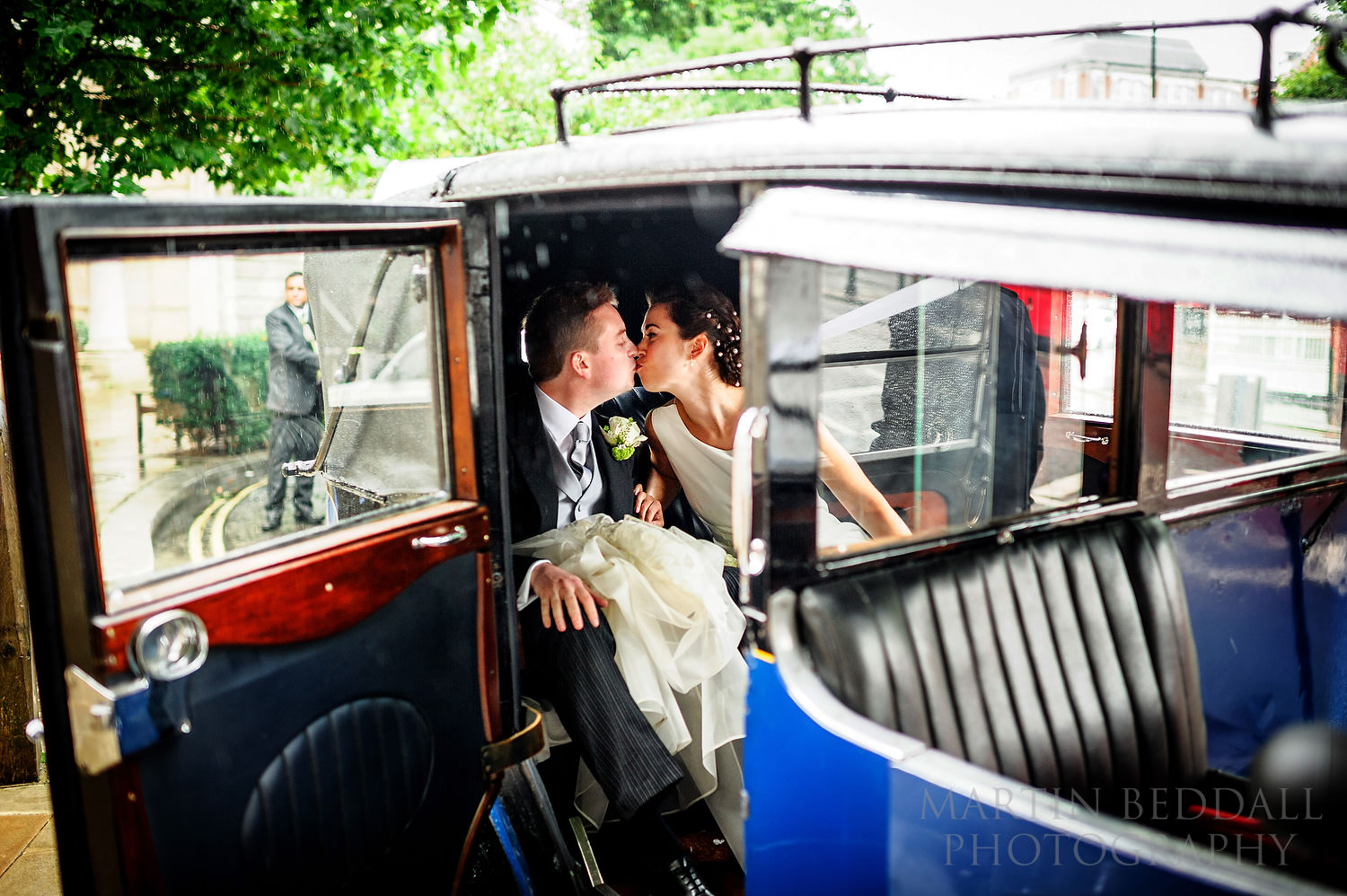 Bride and groom kiss in the wedding car