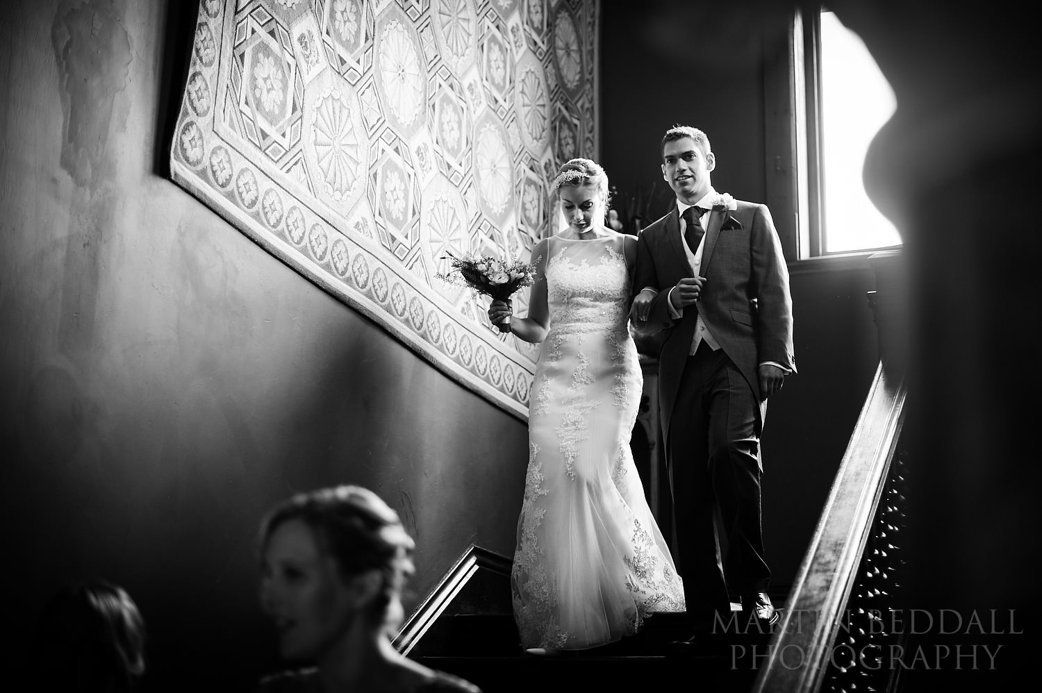 Bride walks down stairs with her brother at Huntsham Court