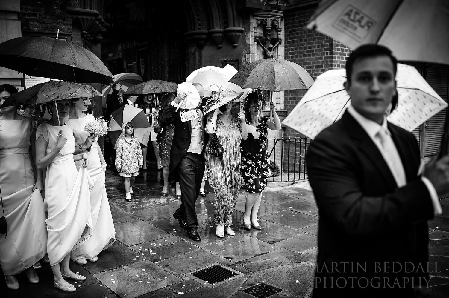 Downpour a sguests leave the church at London wedding