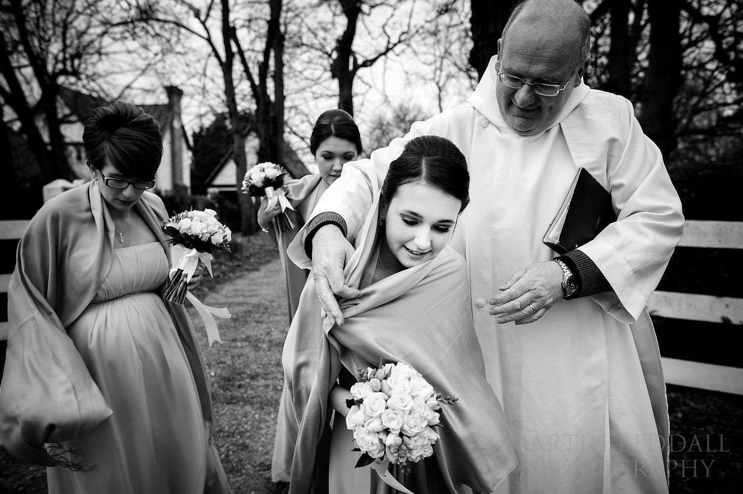 Vicar helps a bridesmaid keep warm