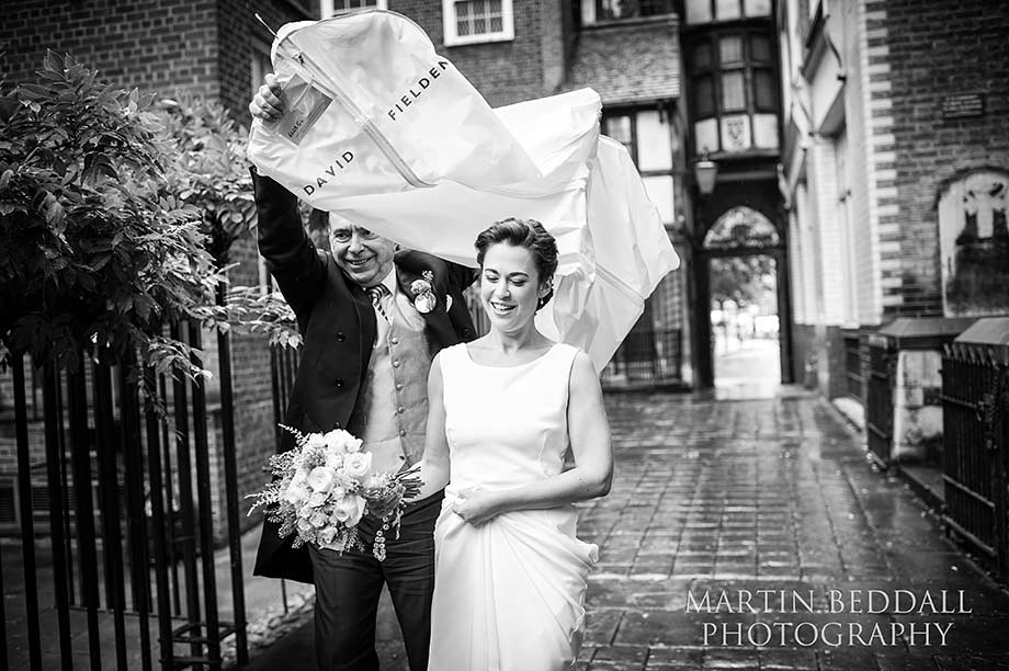 David Fielden dress cver helps keep the rain off the bride as she arrives at the church