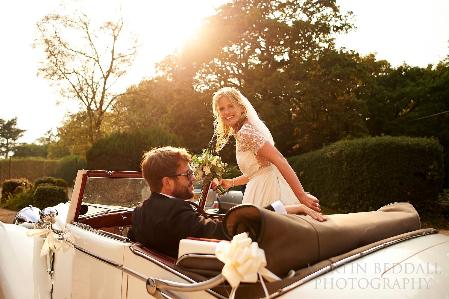 September sunshine as the bride and groom arrive in the vintage wedding car