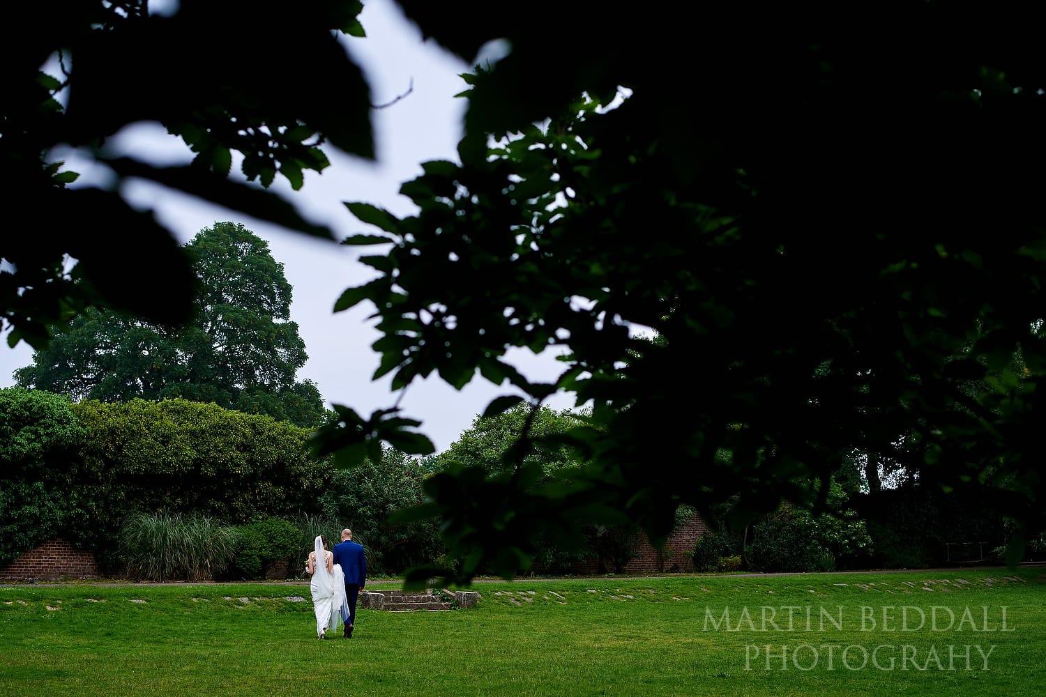 Bride and groom walk in the grounds of Hampton Court House