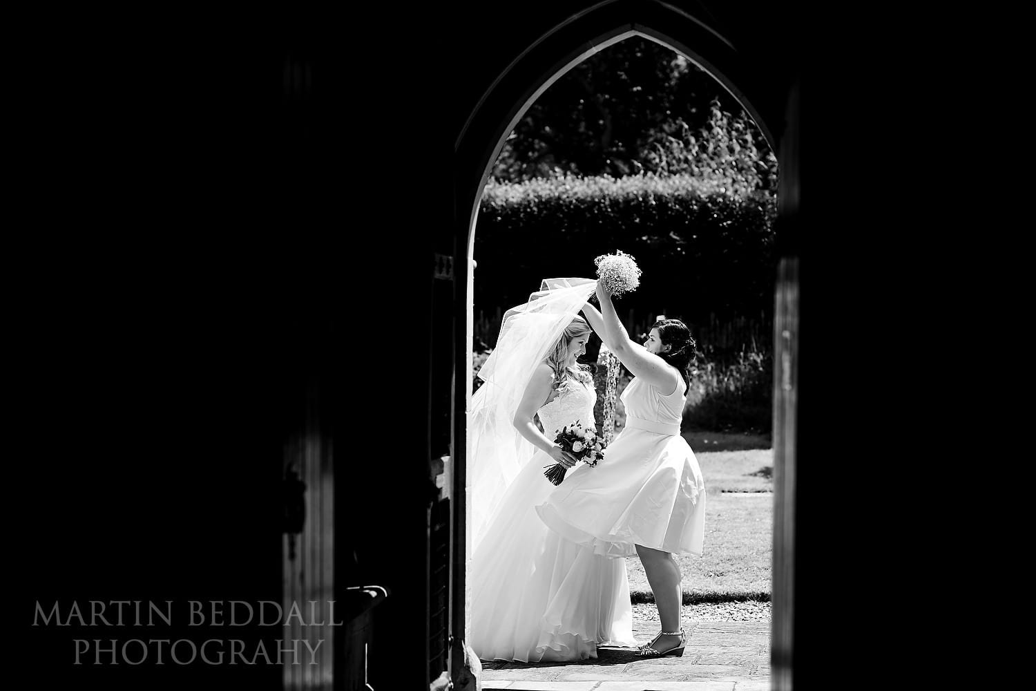 Bride's sister helps fix her veil in the wind