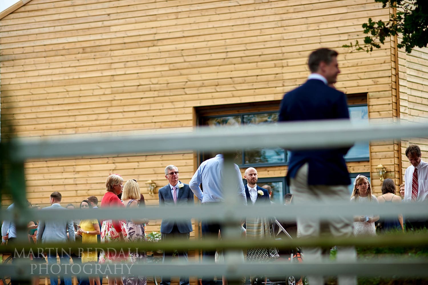 Wedding guests gather outside the ceremony barn at Chafford Park wedding