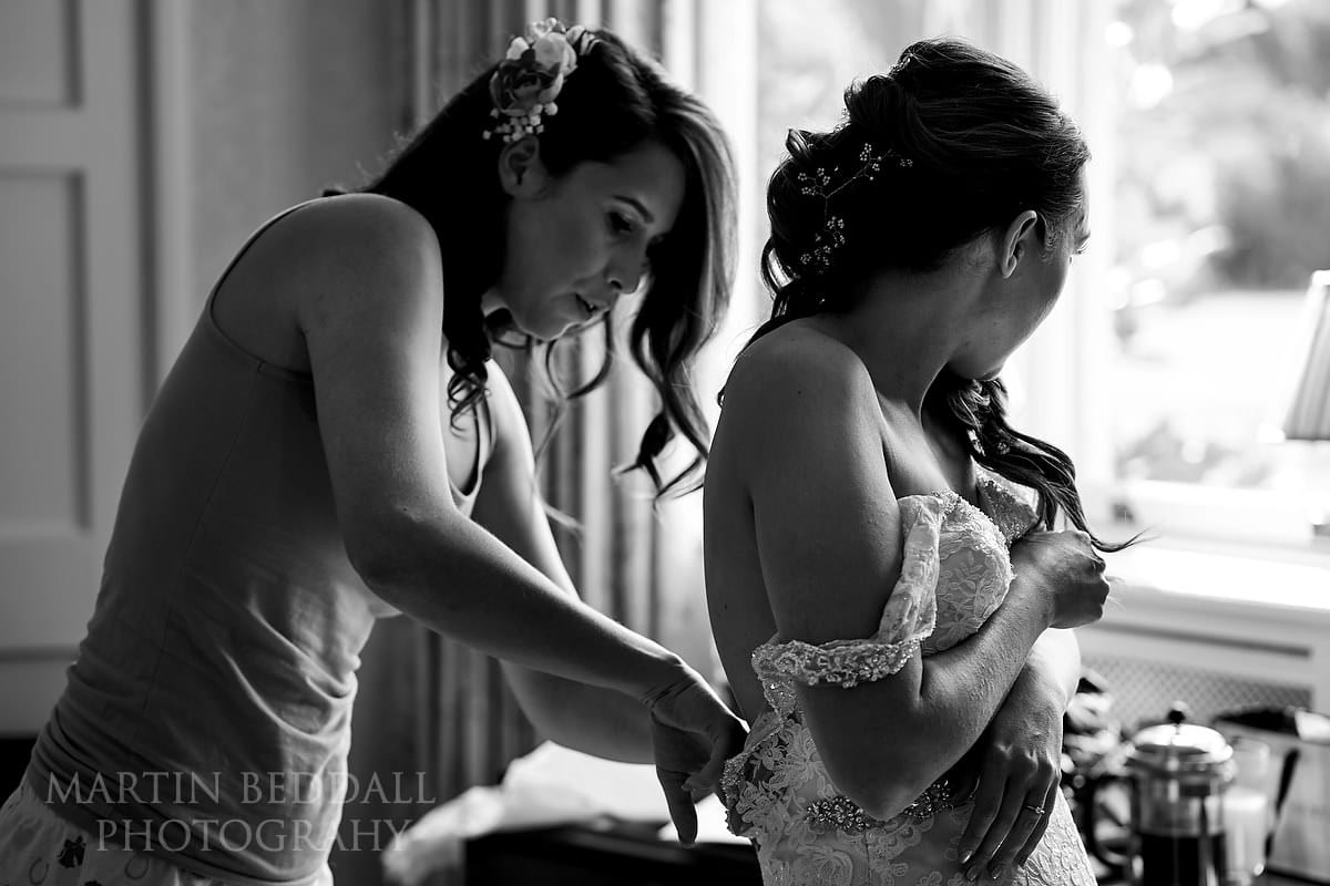 Getting the bride into her wedding dress at Horsted Place