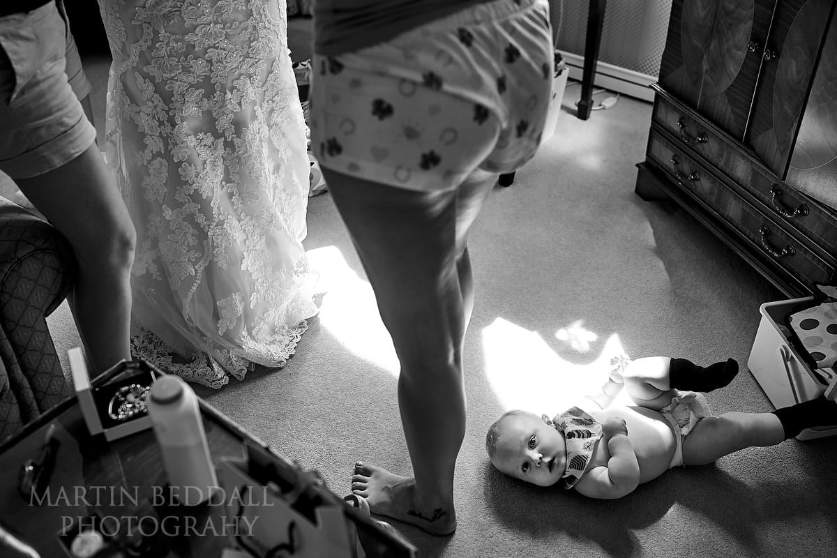 Young son lying on the floor as his mother gets into her wedding dress