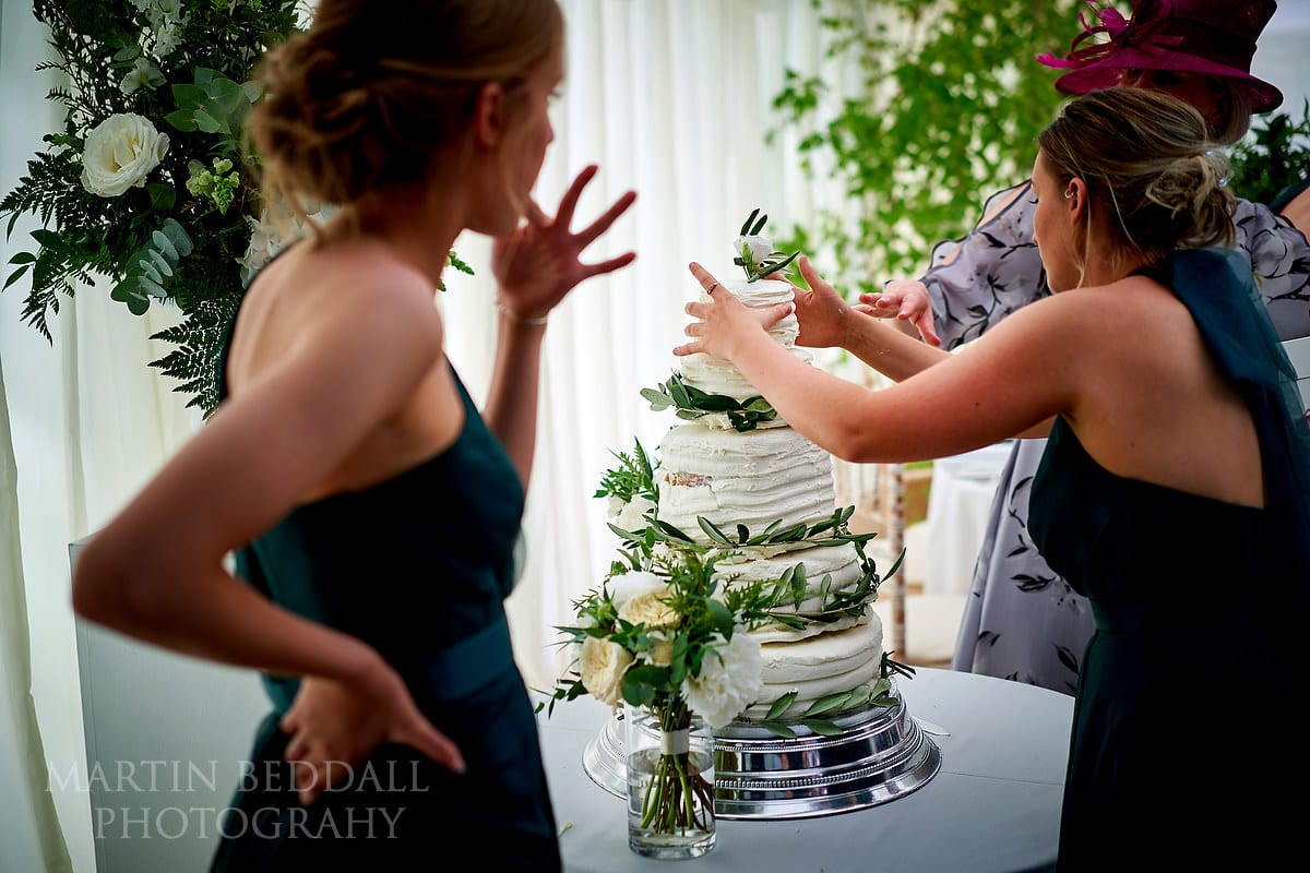 Arranging the wedding cake in Marquee in the garden wedding
