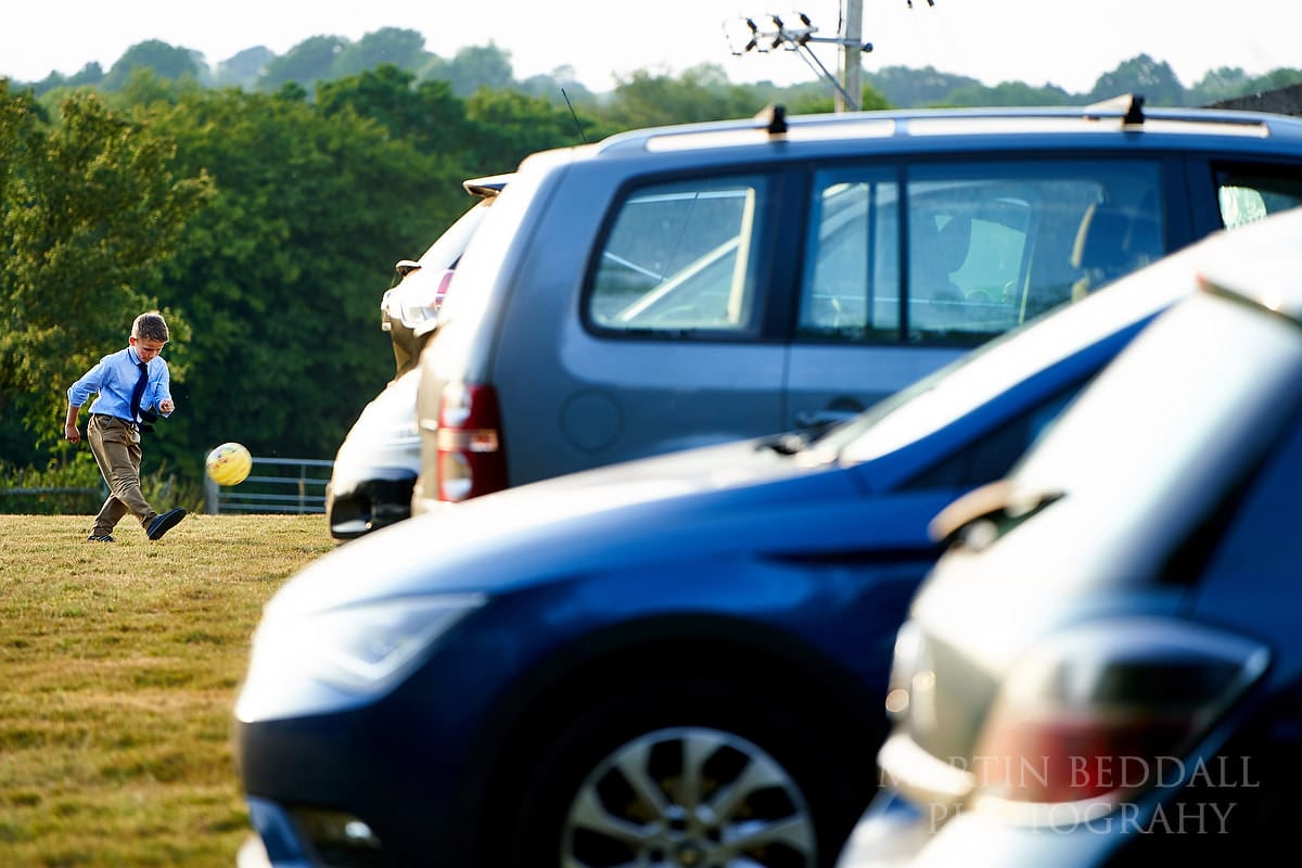 Kicking a football in the field by the cars