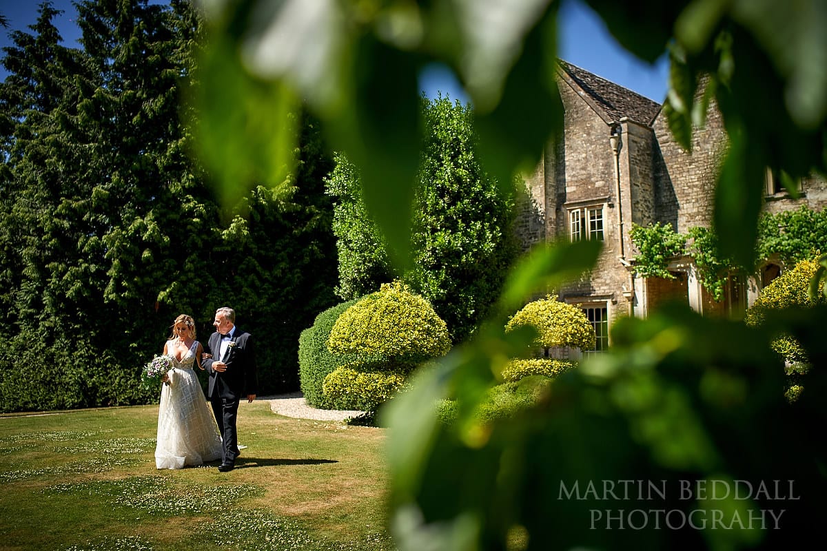Bride escorted across the lawns at Barnsley House by her father