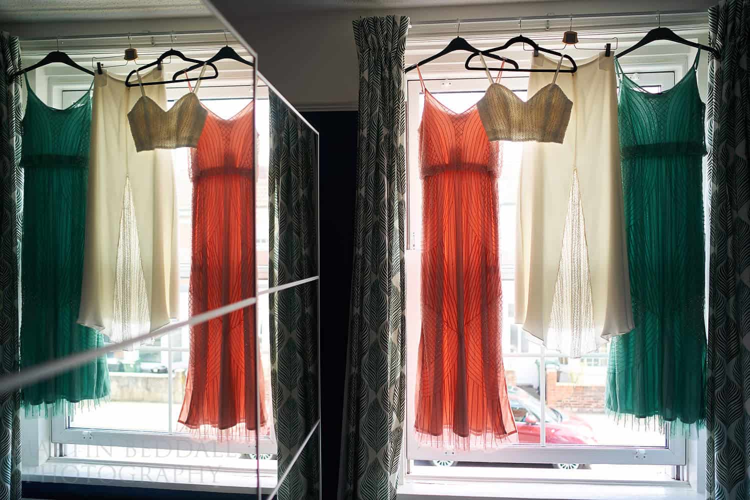 Bride and bridesmaids dresses hanging on the window