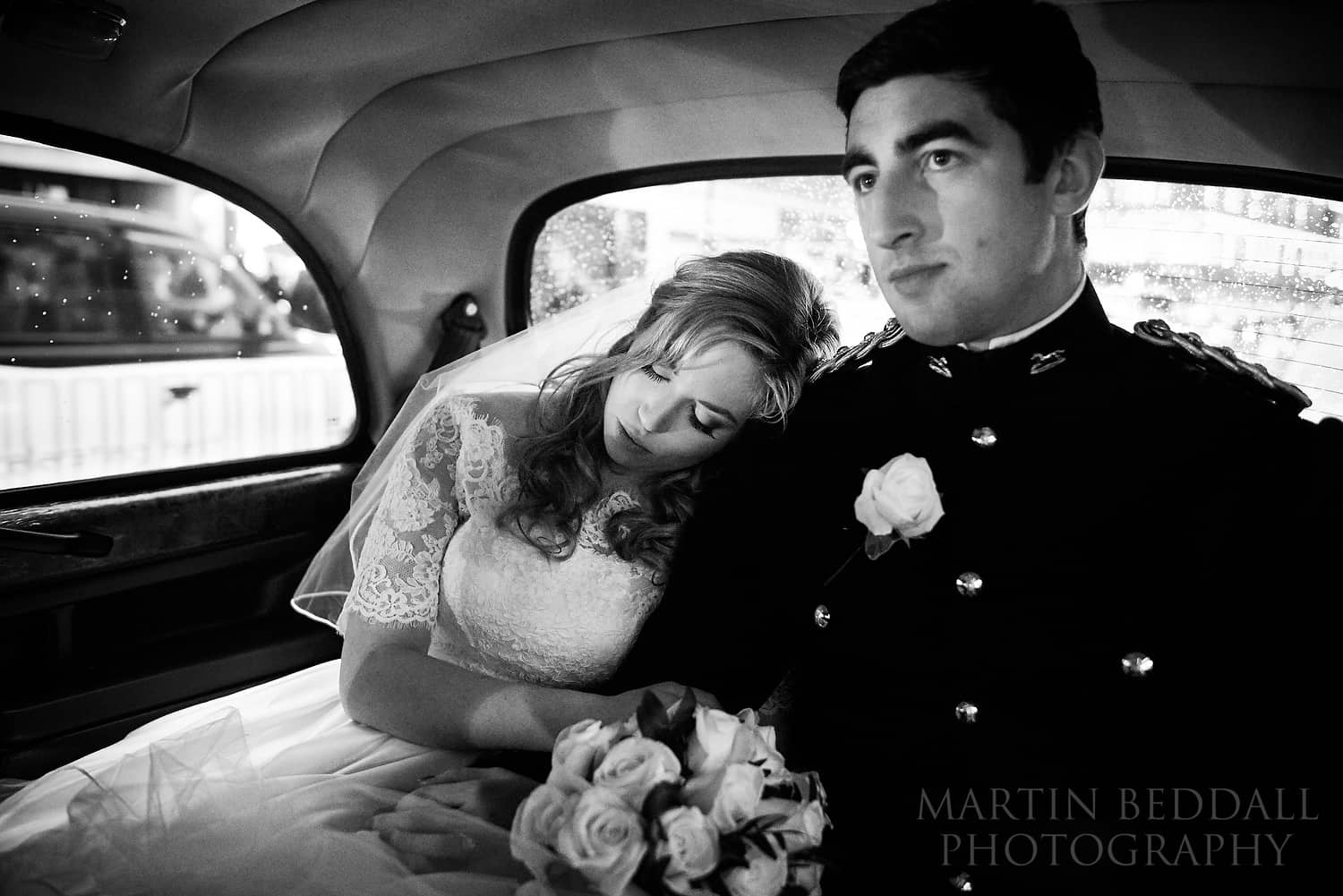 Bride leans her on her husband's shoulfder in the cab