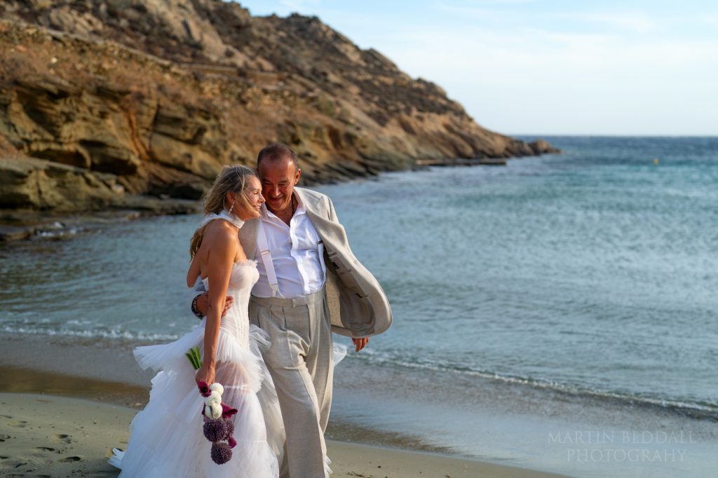 Bride and groom walk along the beach to the ceremony spot