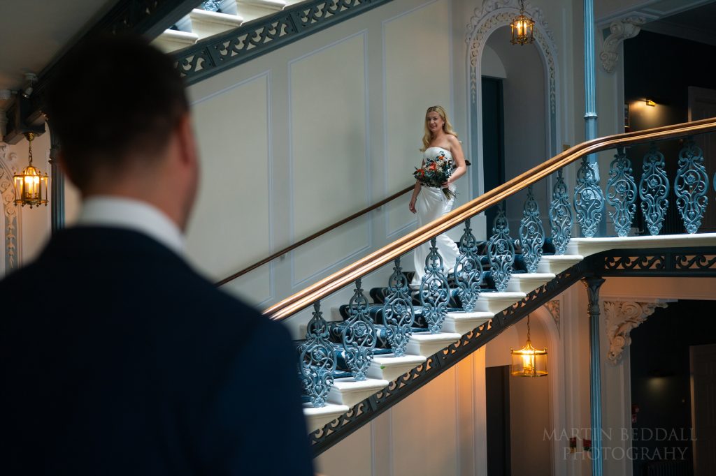 Groom collects the bride on the Grand Hotel staircase