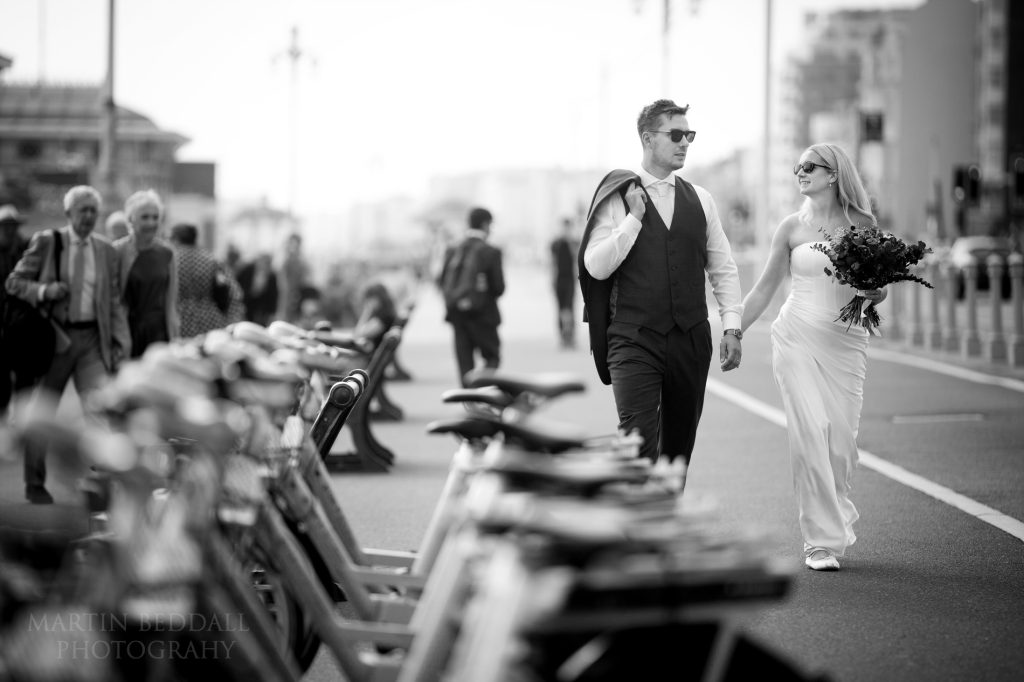 Bride and groom walk along Brighton seafront