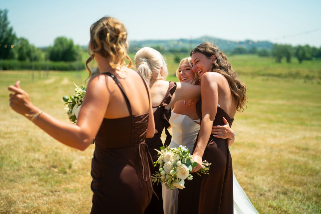 Bridesmaids hug the bride